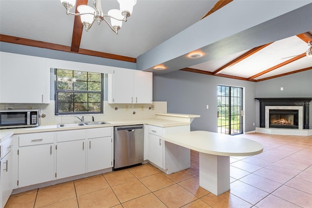 kitchen with a peninsula, a sink, light countertops, appliances with stainless steel finishes, and tasteful backsplash