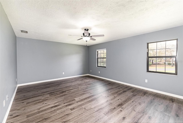 empty room with a textured ceiling, a ceiling fan, baseboards, and wood finished floors