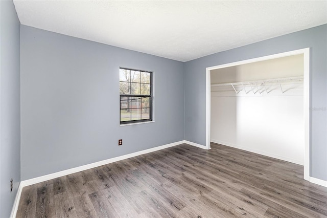 unfurnished bedroom with a closet, baseboards, and wood finished floors