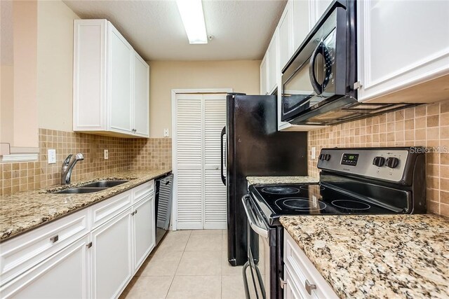 kitchen with light tile patterned floors, black appliances, light stone counters, sink, and white cabinets