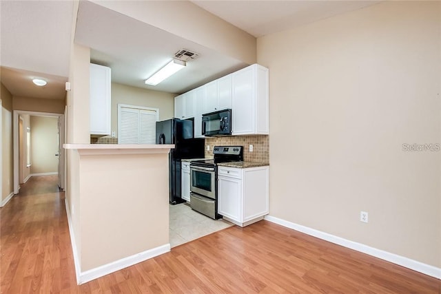 kitchen with light wood-type flooring, black appliances, white cabinetry, and tasteful backsplash