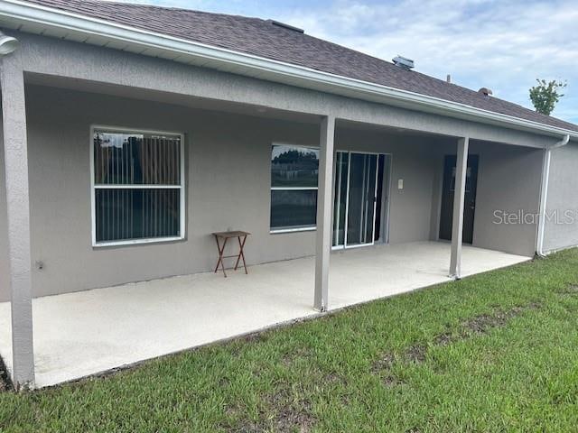 back of house with a yard and a patio