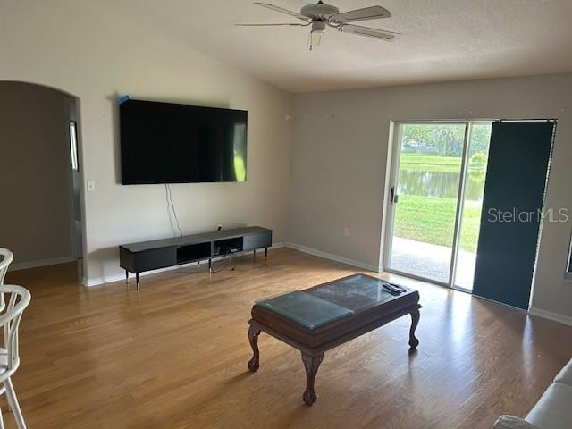 living room with lofted ceiling, hardwood / wood-style floors, ceiling fan, and a textured ceiling