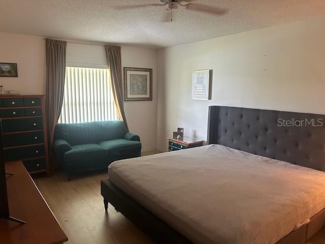 bedroom featuring a textured ceiling, ceiling fan, and hardwood / wood-style flooring