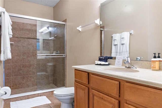 bathroom with a shower with door, vanity, toilet, and tile patterned flooring