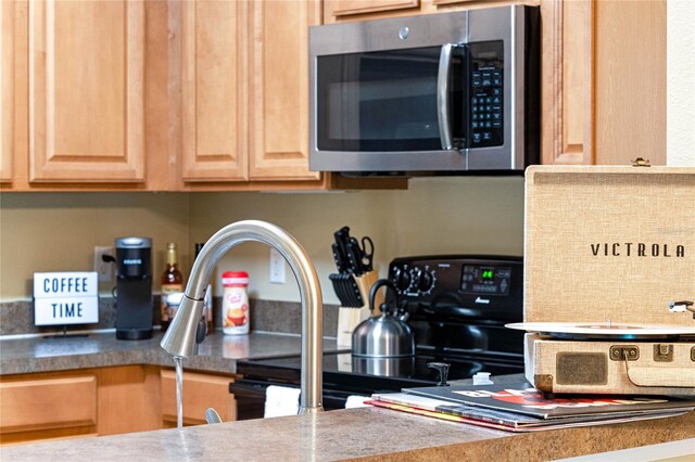 kitchen featuring light brown cabinetry and black stove