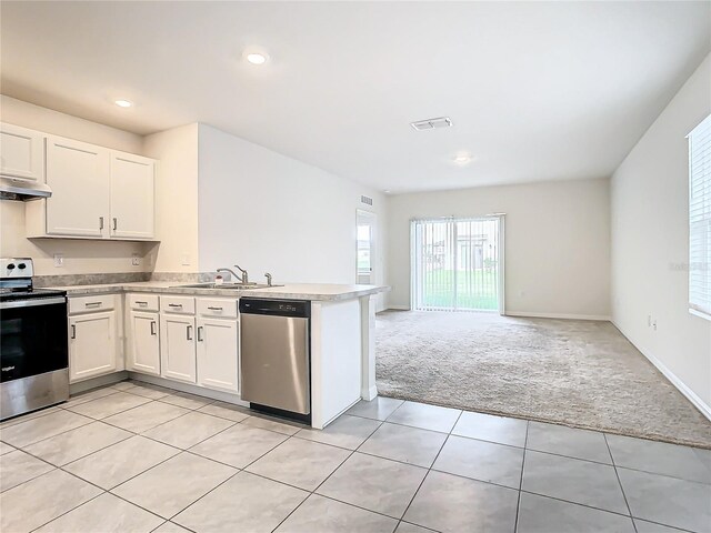 kitchen with light carpet, appliances with stainless steel finishes, sink, and white cabinets