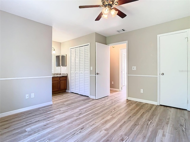 unfurnished bedroom with visible vents, connected bathroom, light wood-style floors, baseboards, and ceiling fan