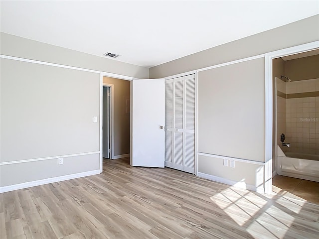 unfurnished bedroom with light wood finished floors, visible vents, baseboards, and a closet