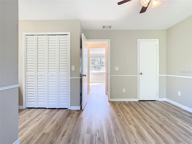 unfurnished bedroom featuring visible vents, wood finished floors, a closet, and baseboards