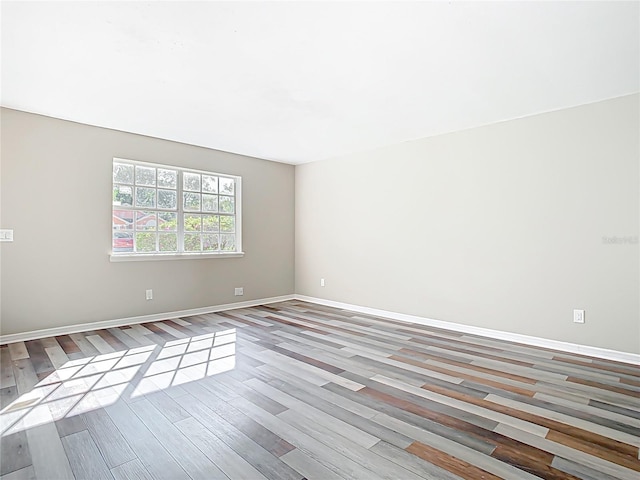 unfurnished room with baseboards and wood finished floors