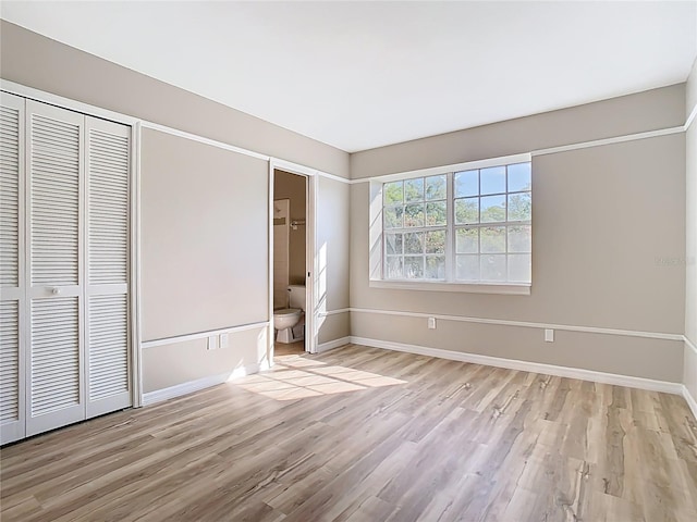 unfurnished bedroom featuring baseboards, light wood-type flooring, and a closet