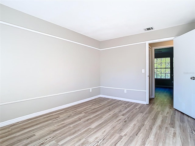 empty room with light wood-style flooring, baseboards, and visible vents