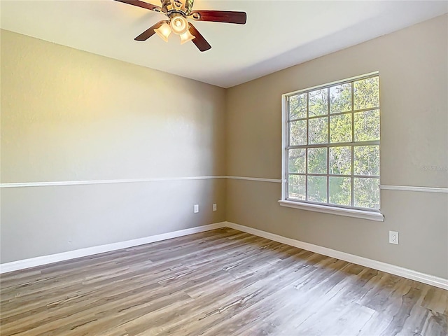 unfurnished room featuring wood finished floors, a ceiling fan, and baseboards