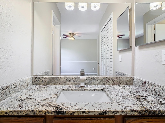 bathroom with vanity, a ceiling fan, and a textured wall