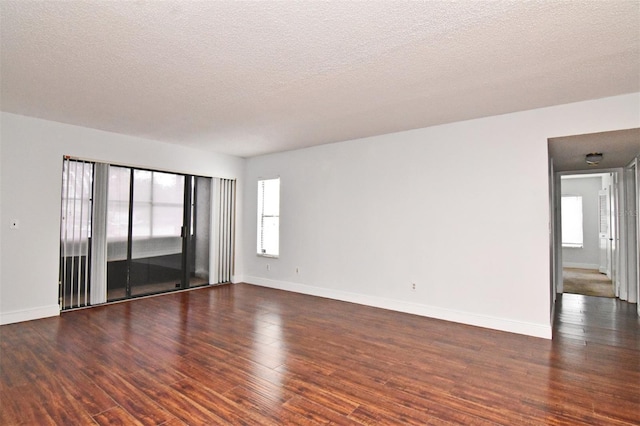 spare room featuring dark hardwood / wood-style floors, a textured ceiling, and a wealth of natural light