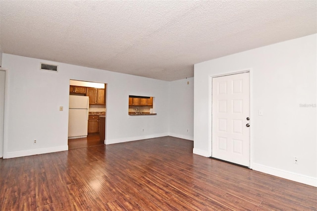 empty room with dark hardwood / wood-style floors and a textured ceiling