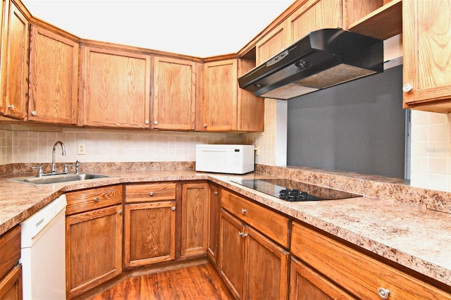 kitchen featuring sink, decorative backsplash, hardwood / wood-style flooring, and white appliances