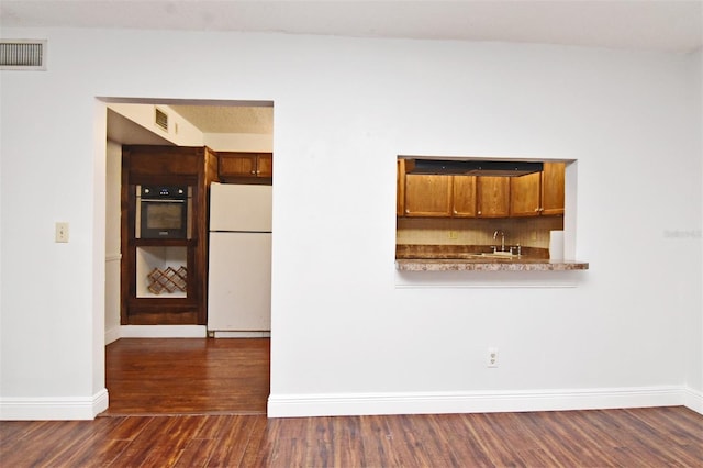 954 Courtyard Ln Unit 11, Orlando, FL 32825 - kitchen with a sink, brown cabinetry, dark wood-type flooring, visible vents, and freestanding refrigerator