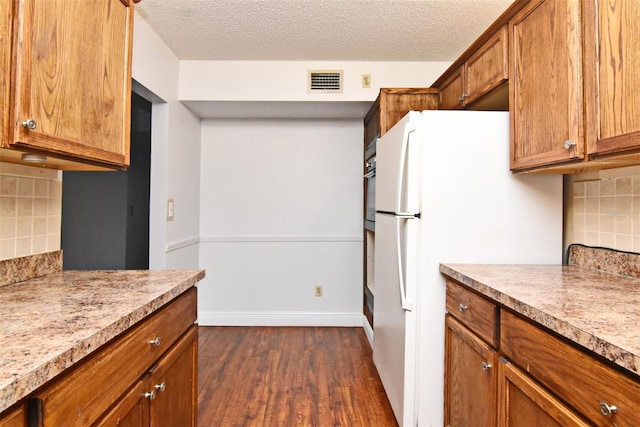 kitchen featuring tasteful backsplash, light stone countertops, a textured ceiling, dark hardwood / wood-style flooring, and white fridge