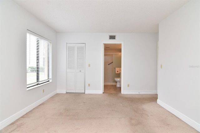 954 Courtyard Ln Unit 11, Orlando, FL 32825 - unfurnished bedroom with connected bathroom, a closet, light carpet, baseboards, and visible vents