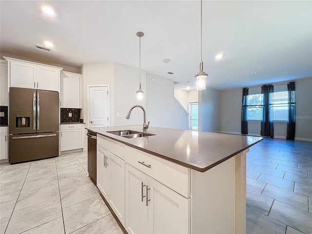 kitchen featuring white cabinets, appliances with stainless steel finishes, a kitchen island with sink, and sink