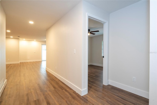 hall featuring baseboards, wood finished floors, and recessed lighting