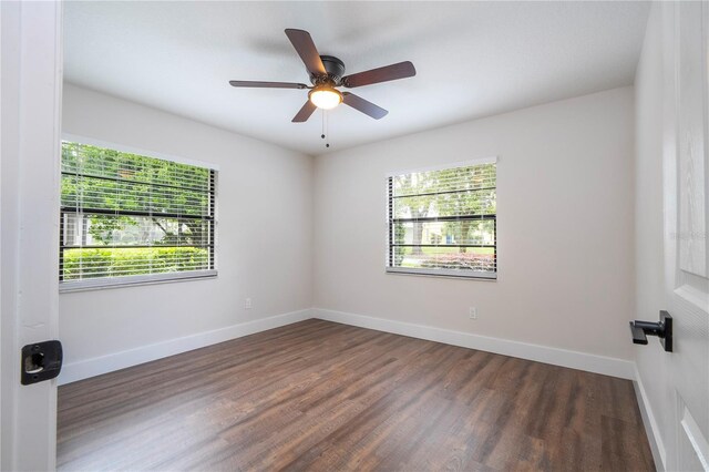 unfurnished room with a ceiling fan, dark wood-style floors, baseboards, and a healthy amount of sunlight