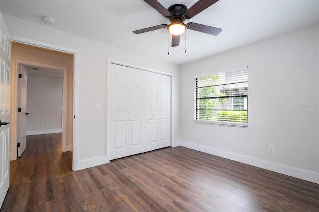 unfurnished bedroom with a closet, dark wood-type flooring, baseboards, and ceiling fan