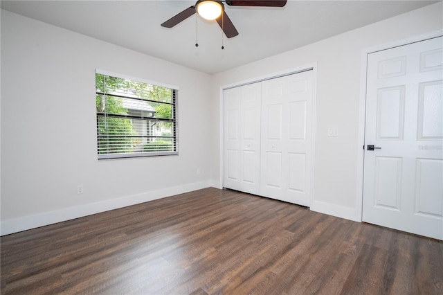 unfurnished bedroom with baseboards, dark wood-style floors, a closet, and ceiling fan
