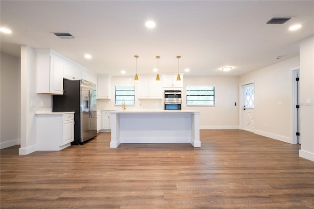 kitchen with pendant lighting, a center island, stainless steel appliances, light wood-type flooring, and white cabinets