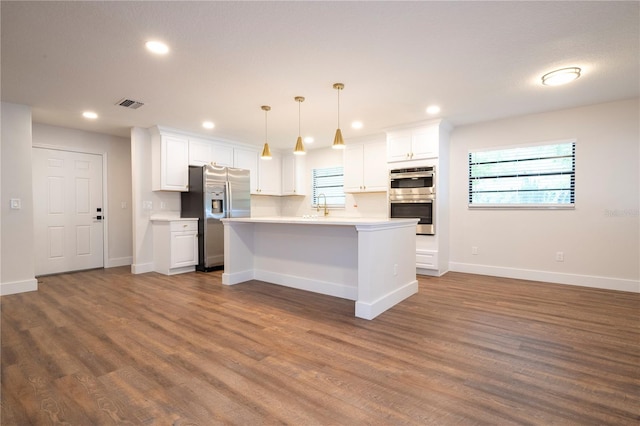 kitchen featuring a center island, decorative light fixtures, hardwood / wood-style floors, stainless steel appliances, and white cabinetry