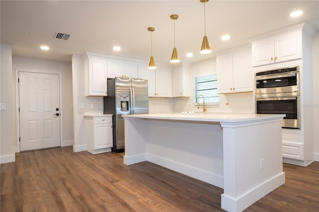 kitchen featuring dark hardwood / wood-style floors, white cabinetry, stainless steel appliances, and hanging light fixtures