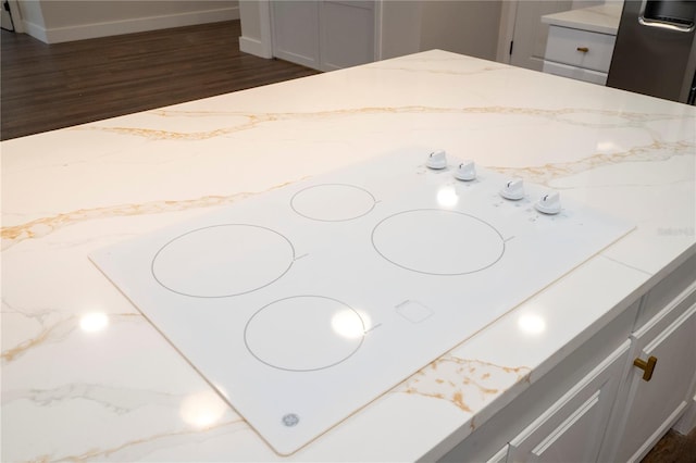 interior details featuring white electric stovetop, light stone countertops, and dark wood finished floors