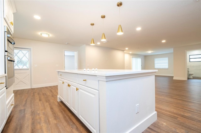 kitchen with hardwood / wood-style flooring, a center island, oven, white cabinetry, and pendant lighting