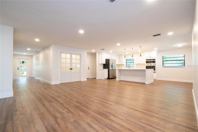 unfurnished living room with sink and light hardwood / wood-style flooring