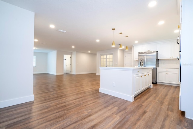 kitchen featuring a kitchen island, stainless steel refrigerator with ice dispenser, hanging light fixtures, hardwood / wood-style flooring, and white cabinets