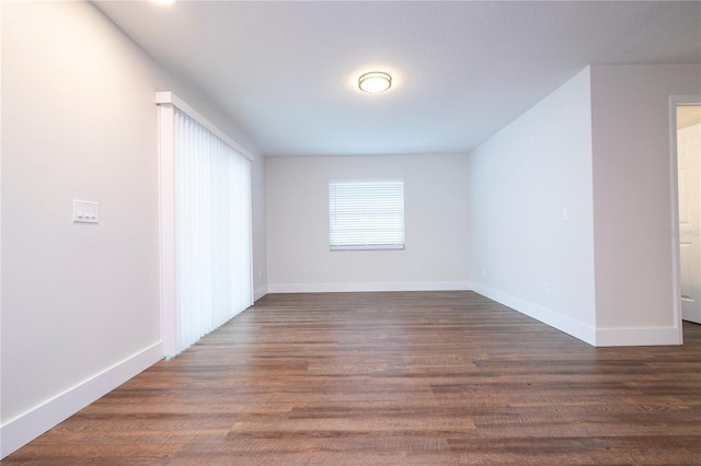 unfurnished room with baseboards and dark wood-style flooring