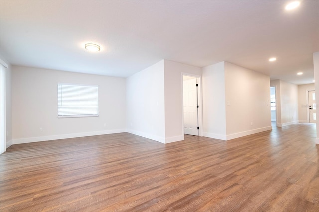 spare room with baseboards, wood finished floors, and recessed lighting