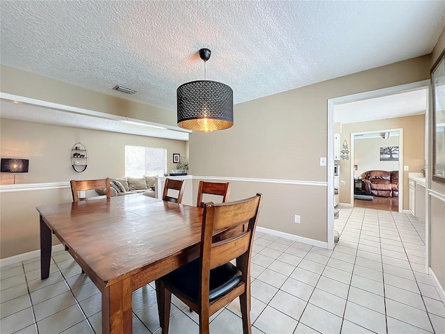 dining area with a textured ceiling and light tile patterned floors