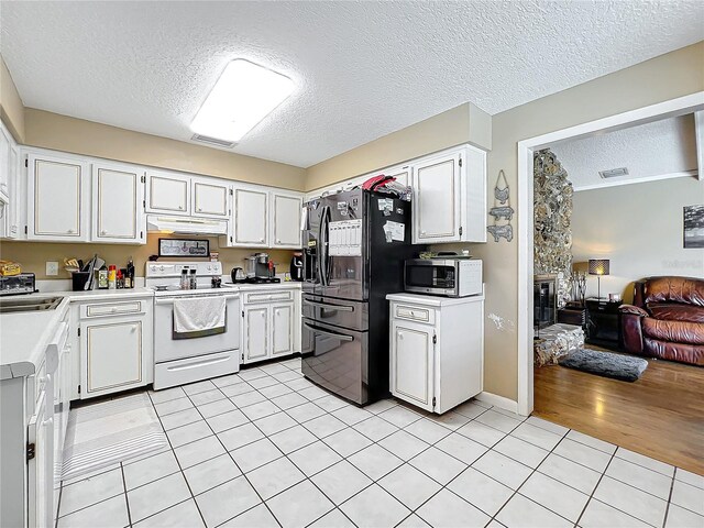 kitchen with black fridge, white electric range oven, white cabinetry, and light hardwood / wood-style floors