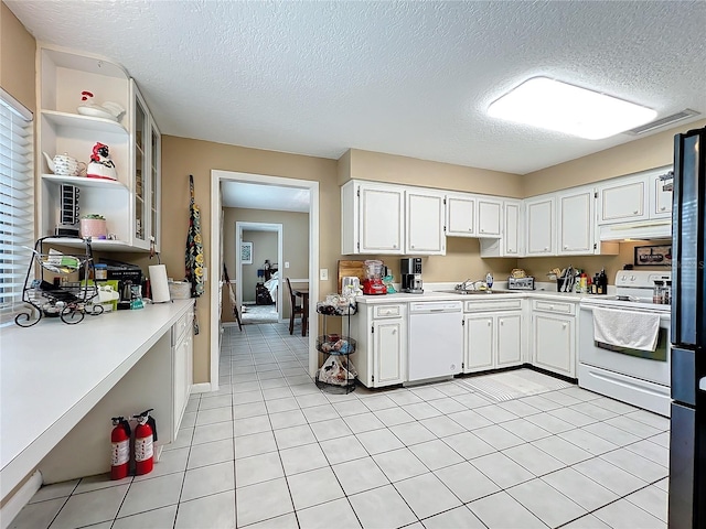 kitchen with a textured ceiling, white appliances, light tile patterned floors, sink, and white cabinetry