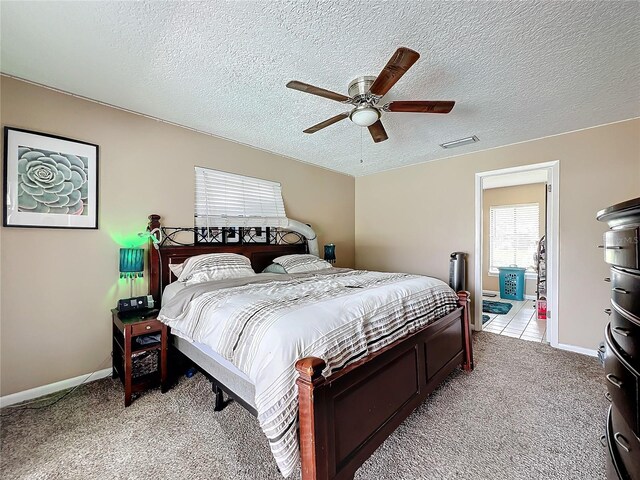 bedroom featuring a textured ceiling, ceiling fan, and light colored carpet