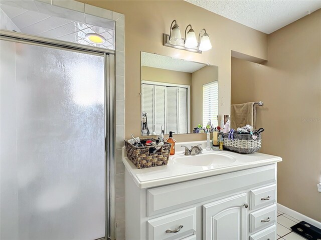 bathroom featuring tile patterned floors, an enclosed shower, a textured ceiling, and vanity