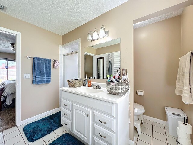 bathroom featuring a textured ceiling, vanity, a shower with door, tile patterned flooring, and toilet