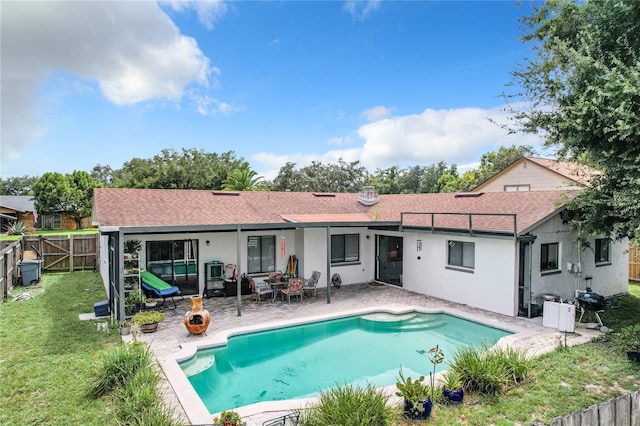 rear view of house with a lawn, a fenced in pool, and a patio