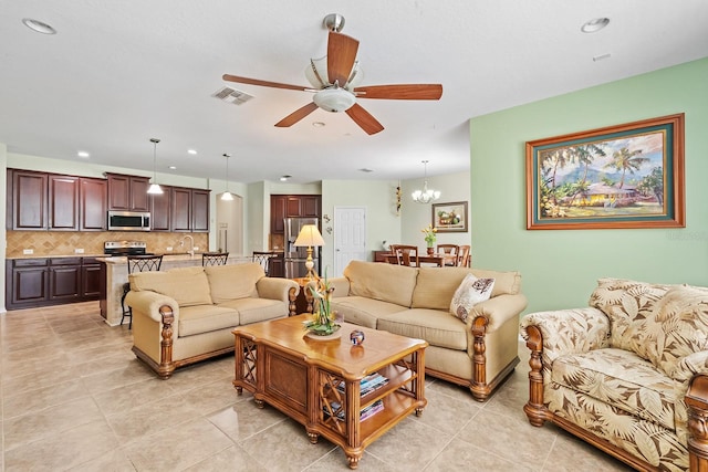 living room featuring light tile patterned floors, sink, and ceiling fan with notable chandelier