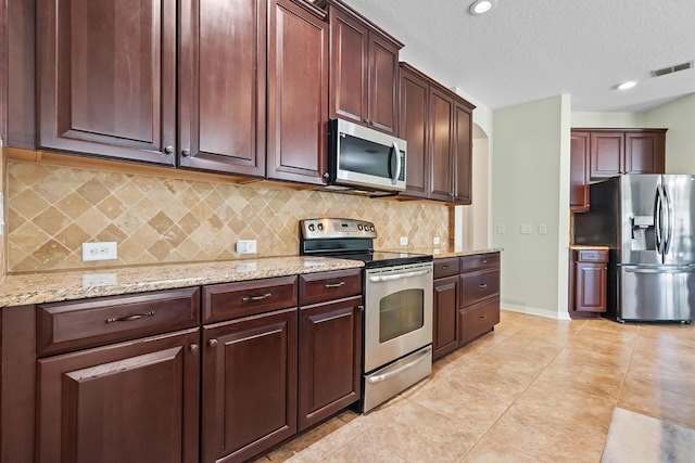 kitchen featuring appliances with stainless steel finishes, decorative backsplash, light tile patterned flooring, a textured ceiling, and light stone counters