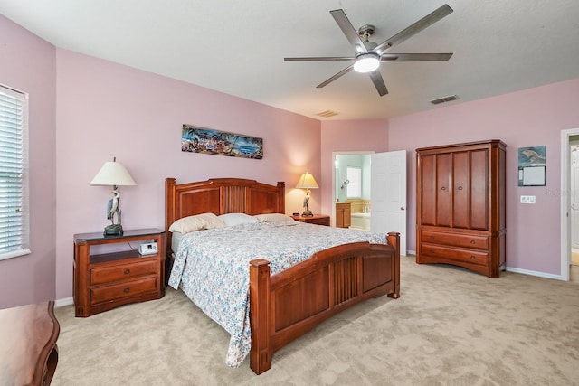 bedroom featuring light carpet, ceiling fan, multiple windows, and ensuite bath