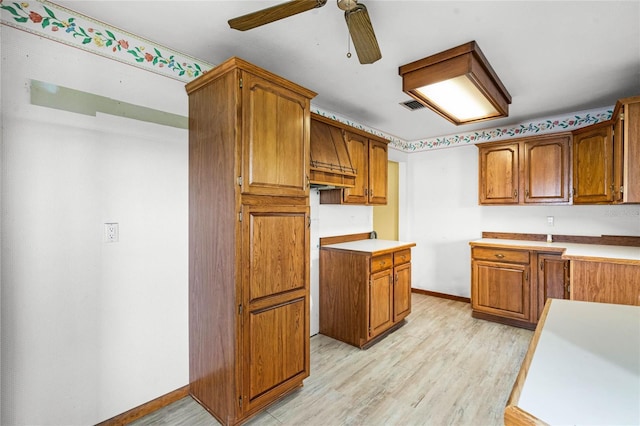 1005 Crescent Pkwy, Deland, FL 32724 - kitchen featuring light wood finished floors, brown cabinetry, a ceiling fan, baseboards, and visible vents